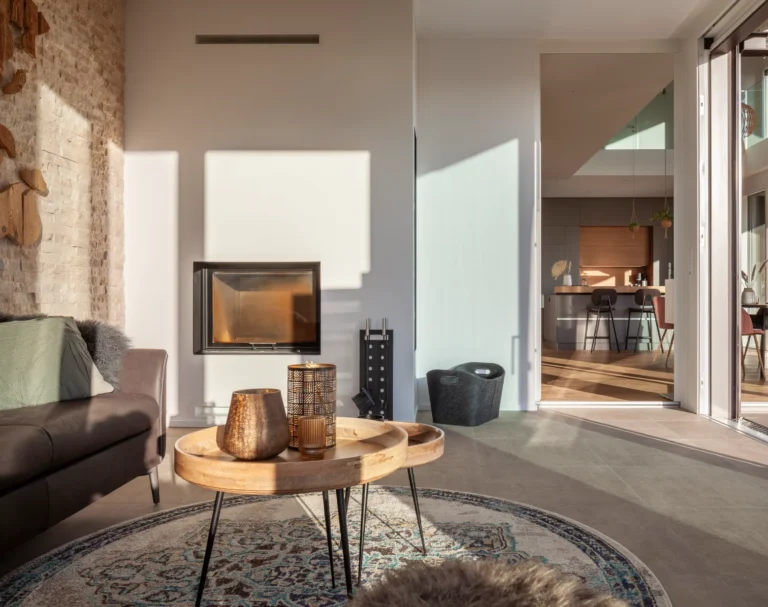 warm, edel und modern eingerichtete Orangerie eines Wohnhauses mit Cheminee in warmen Licht.