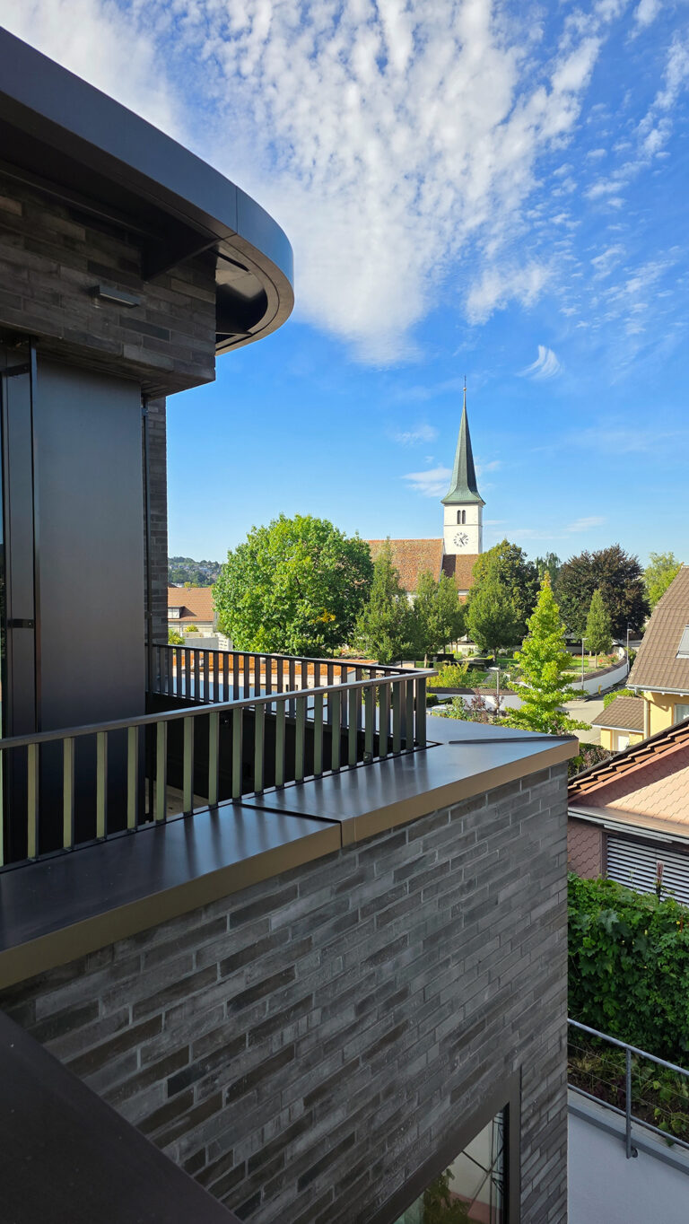 Foto eines Ausschnittes eines Mehrfamilienhauses mit Blick auf den Kirchturm.