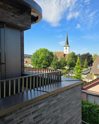 Foto eines Ausschnittes eines Mehrfamilienhauses mit Blick auf den Kirchturm.