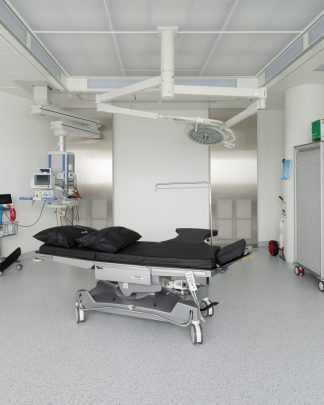 Foto eines modernen hellen Behandlungsraumes mit weissen Wänden, hellem Boden und schwarzer Liege.