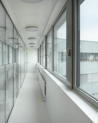 Foto eines Ganges zwischen langer Fensterfront und langer Glasfront.