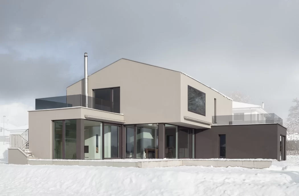 Seitenansicht eines grosszügigen und edlen Einfamilienhauses im Schnee.